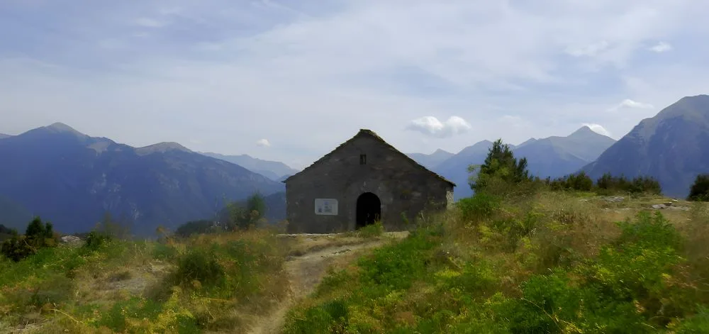 The Virgen de la Peña Hermitage, Tella, Huesca, Spain – The Land of the Witches. The image captures a picturesque stone chapel perched on a hillside, overlooking the rugged Pyrenean landscape.