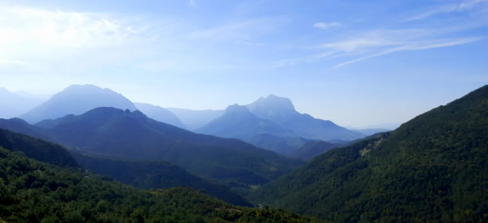 Scenic landscape of Tella, Huesca, Spain. The image captures the breathtaking view of this remote mountain village in the Pyrenees, surrounded by lush forests, rolling hills, and rugged peaks.