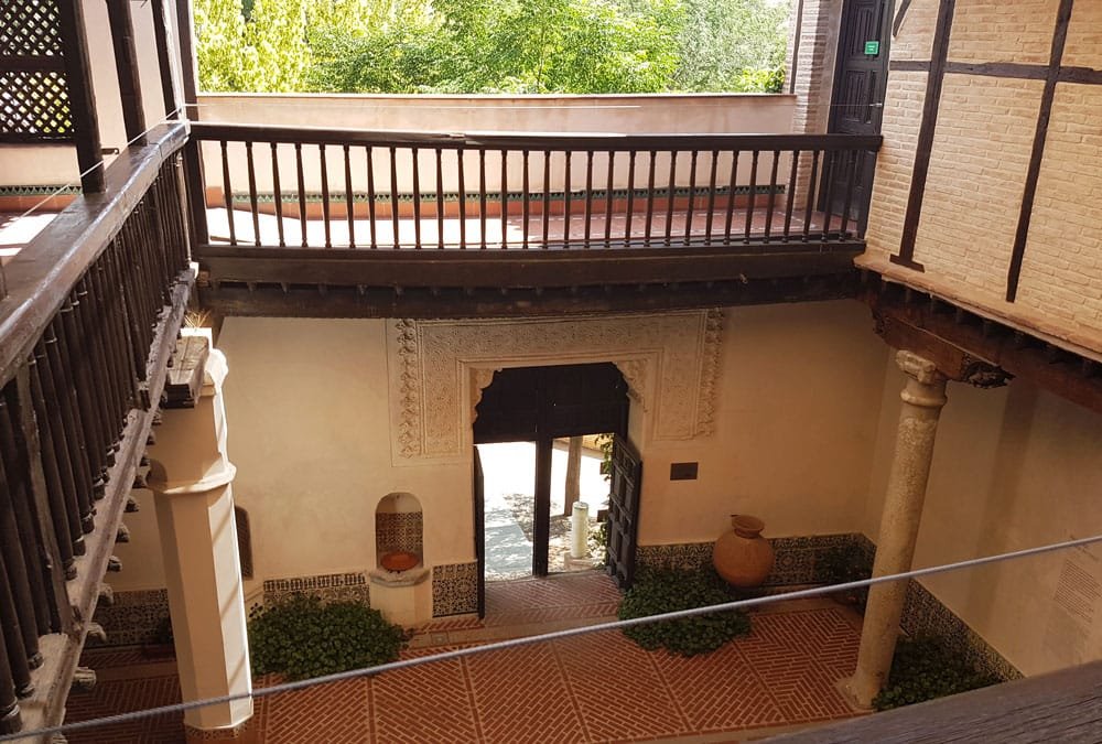 Interior patio of the El Greco Museum in Toledo, Spain, featuring traditional Spanish architecture with stone archways and wooden balconies.
