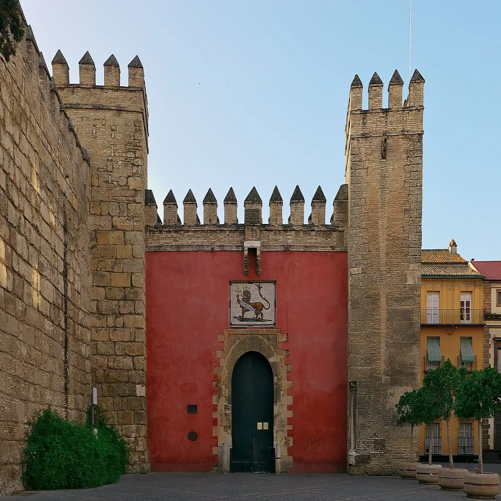 Entrance to the Alcázar of Seville through the Puerta del León, a gateway adorned with a ceramic lion, welcoming visitors to a historical tapestry woven with centuries of Andalusian splendor.