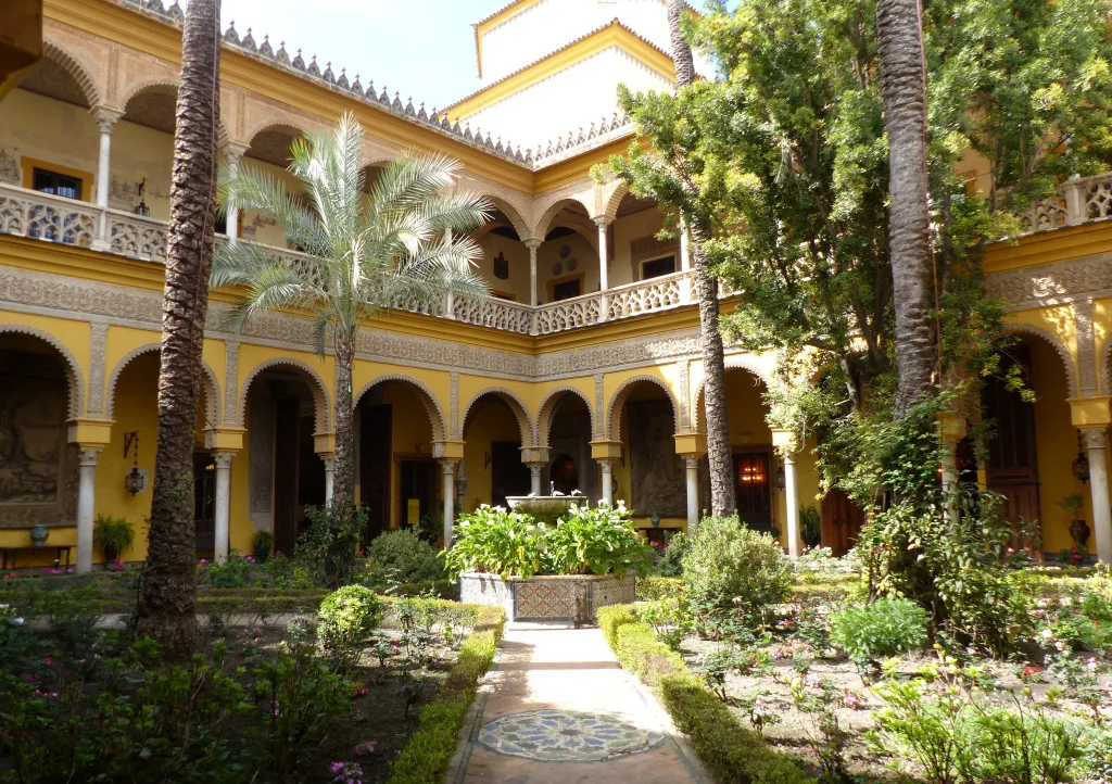 Secluded Splendor: The courtyard of the Palacio de las Dueñas in Seville, a tranquil haven where Andalusian nobility mingles with the cool shade of orange trees.