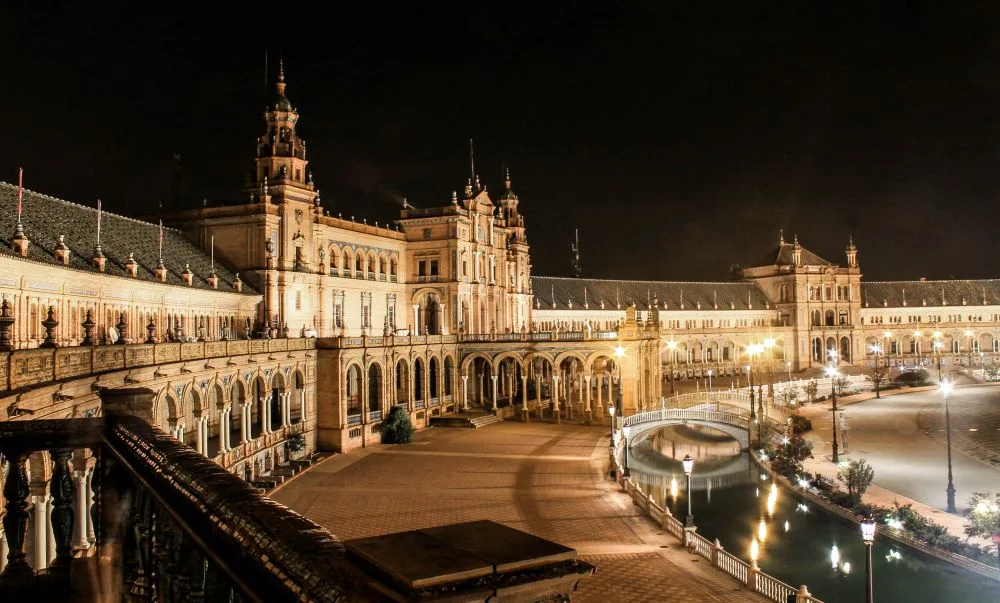 Under the Veil of Night: The Plaza de España in Seville, illuminated by the gentle glow of lanterns, becomes a nocturnal wonder, its silhouette a dance of light and shadow against the evening tapestry. Star Wars Seville