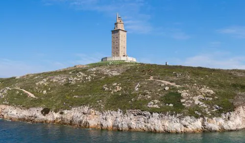 The Tower of Hercules in A Coruña, Galicia, Spain, a striking example of Roman ruins in Spain, stands tall against a vibrant blue sky. This Spanish Roman ruin, a UNESCO World Heritage Site, is the oldest functioning lighthouse in the world, showcasing the architectural ingenuity of ancient Rome.