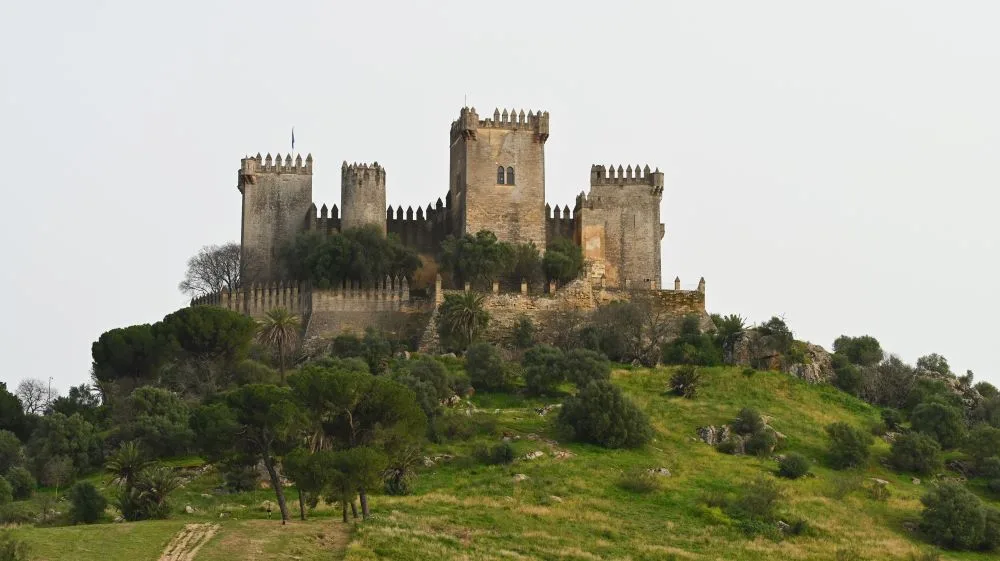 Castle of Almodóvar del Río, Córdoba, Spain [Photograph Edited]. Credit: Krzysztof Ziarnek, Kenraiz. Wikimedia Commons. Licensed under CC BY-SA 4.0. The image captures the majestic Castle of Almodóvar del Río, located in the province of Córdoba, Andalusia. The castle, perched on a hill overlooking the Guadalquivir Valley, is an iconic example of medieval architecture with a rich history. It is a popular tourist attraction known for its strategic position and stunning views of the surrounding landscape. The photograph highlights the grandeur and historical significance of this fortress.