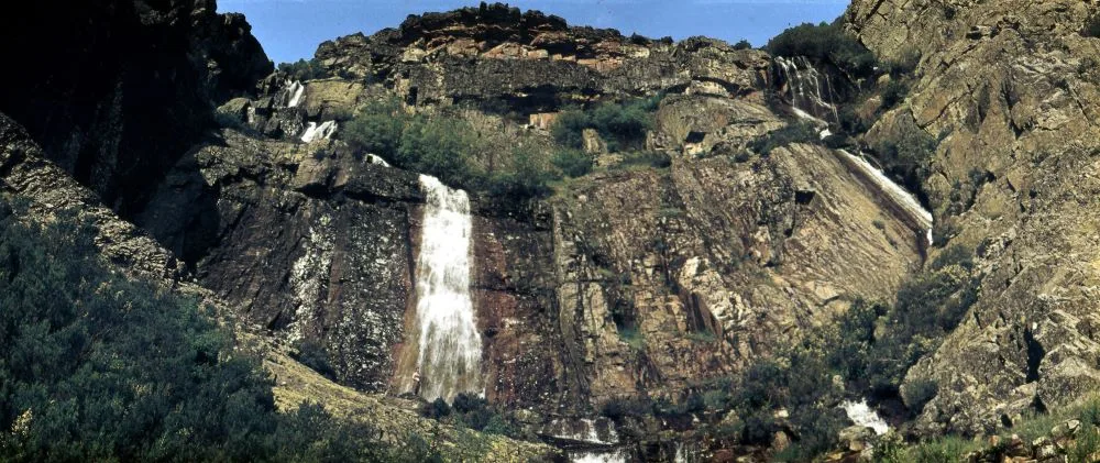 Chorreras de Despeñalagua waterfall in Valverde de los Arroyos, Spain, cascading down rugged quartzite rock formations, surrounded by lush natural scenery.