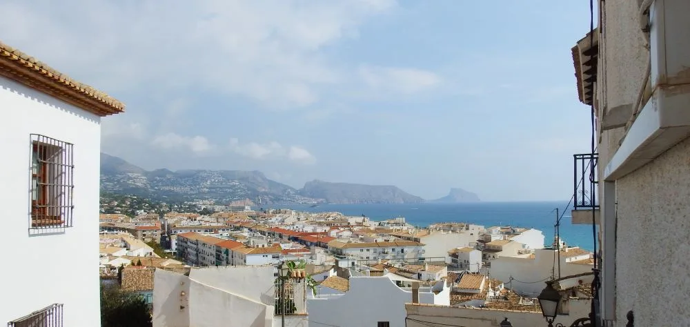 A captivating view of Altea, Alicante, Spain, featuring its iconic whitewashed houses, narrow cobblestone streets, and a glimpse of the Mediterranean Sea.