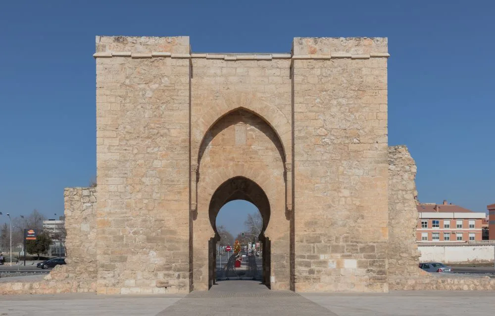 A historic view of Puerta de Toledo in Ciudad Real, Castilla-La Mancha, Spain, highlighting its medieval stone arches and defensive towers, remnants of the city's fortified past.