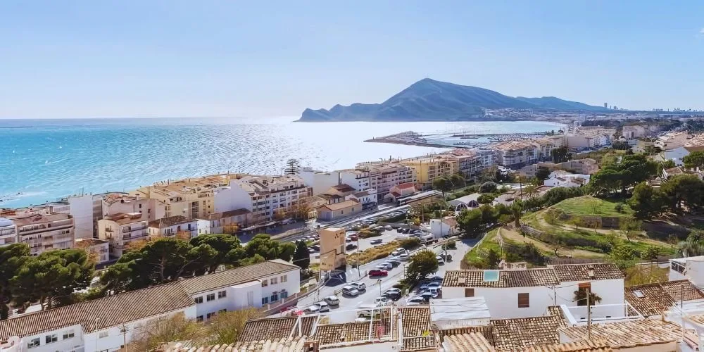 A panoramic view of Altea, Alicante, Spain, featuring its iconic whitewashed houses, the blue-domed church, and the Mediterranean coastline.