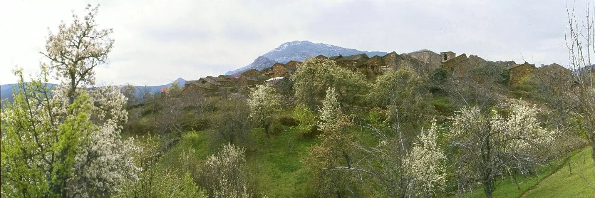 A panoramic view of Valverde de los Arroyos, Spain, with the towering Ocejón Peak in the background, highlighting the village’s traditional black slate architecture and its picturesque mountain setting.